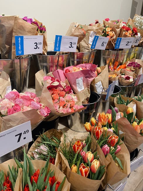 A display of freshly arranged flower bouquets at a florist, featuring a variety of vibrant flowers including pink roses, orange and yellow tulips, and mixed seasonal blooms wrapped in brown kraft pape